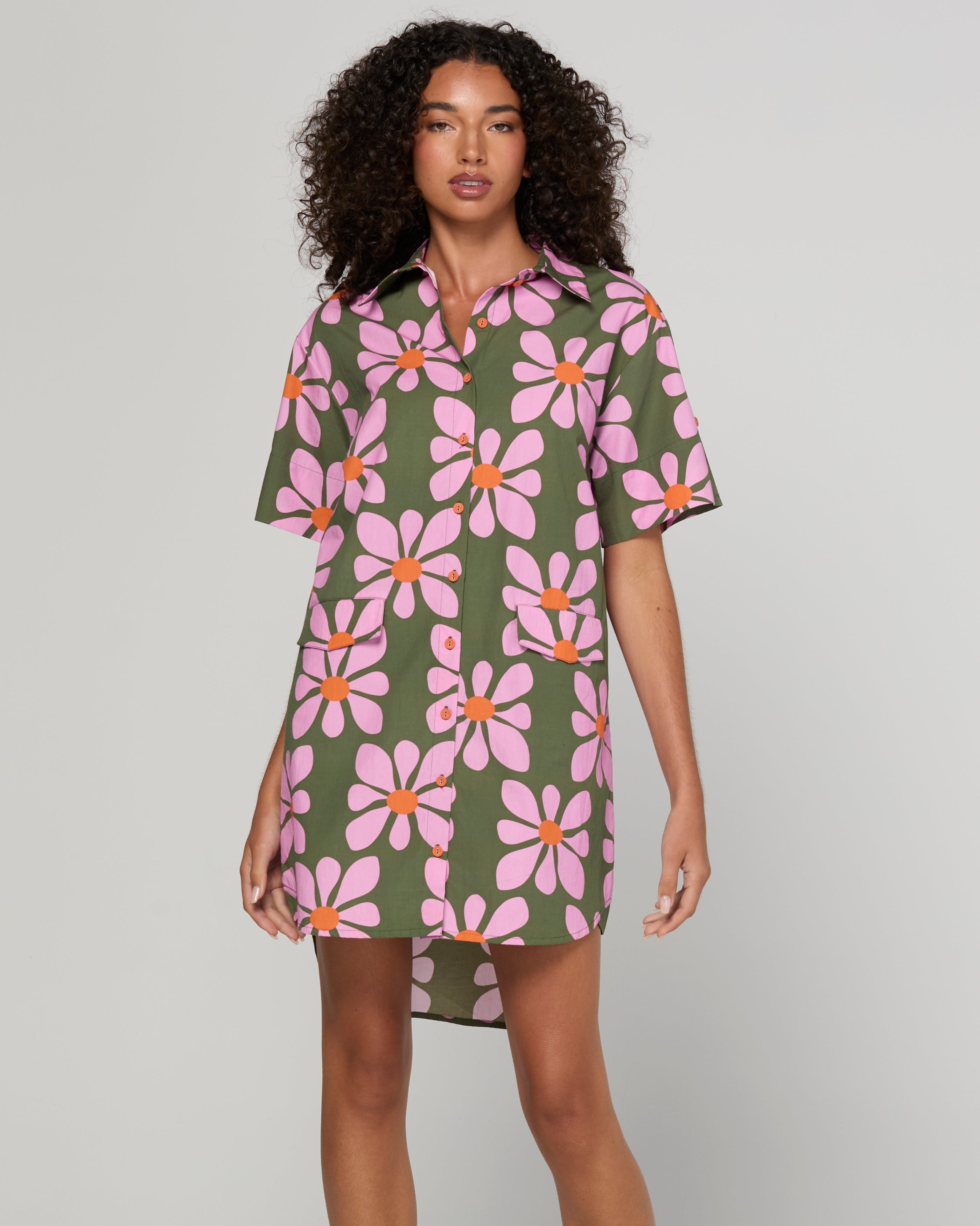 Woman wearing a floral dress with pink flowers on a plain background