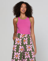 Woman wearing a pink top and green floral pants on a gray background