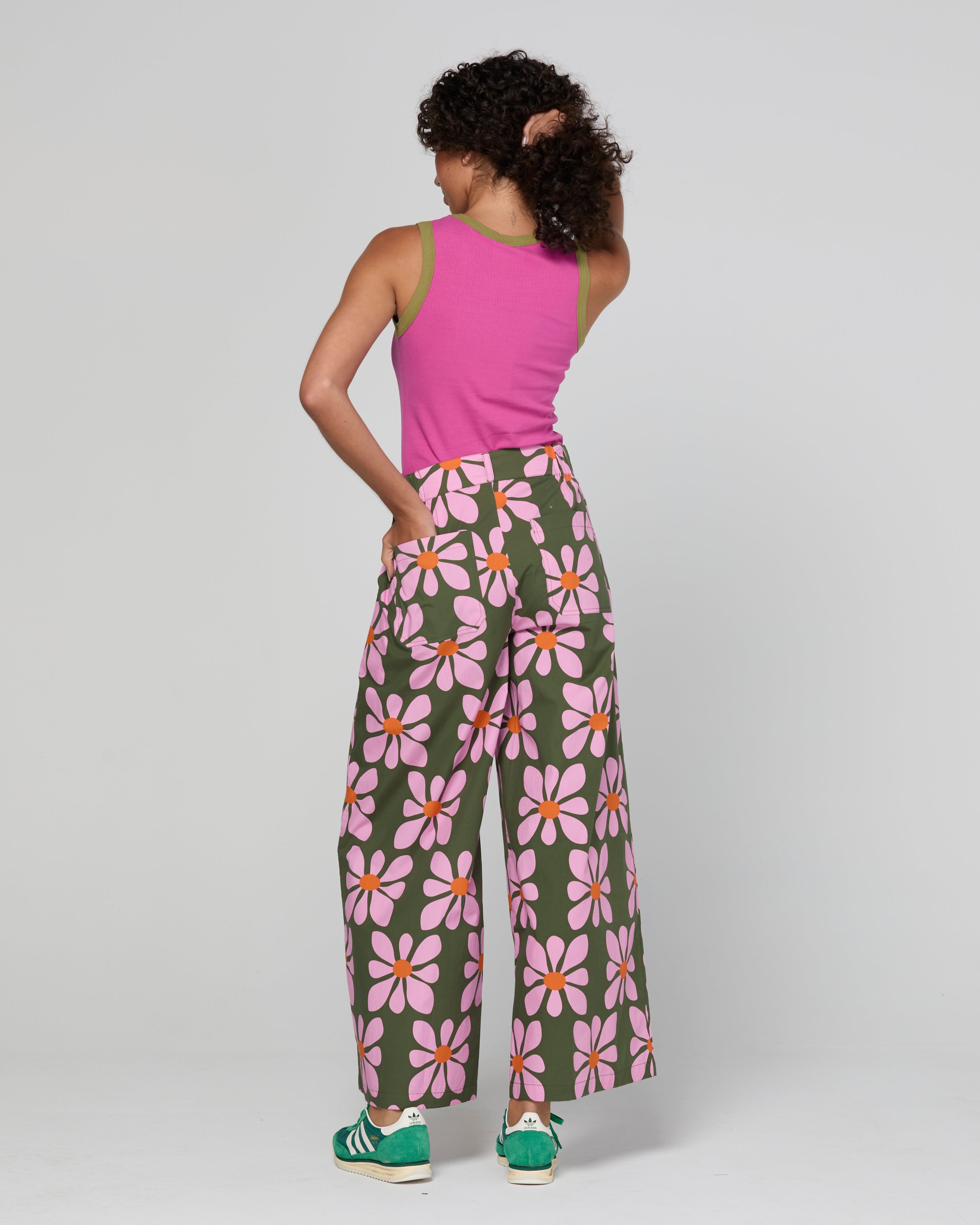 Person wearing a pink sleeveless top and floral pants on a white background