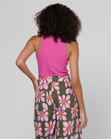 Person wearing a pink sleeveless top and floral pants on a plain background