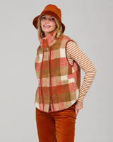 Woman wearing a rust-colored orange corduroy hat on a gray background