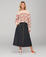 Woman wearing a flower patterned cream sweater and dark denim skirt