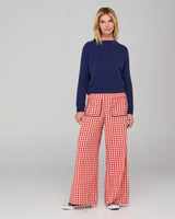 Woman wearing a navy jumper and red checkered pants on a gray background