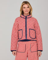 Woman wearing a red and white checkered quilted jacket and pants set on a grey background
