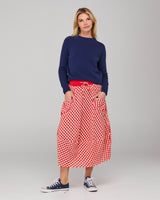Woman wearing a navy sweater and red checkered skirt on a gray background
