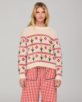 Woman wearing a cream patterned jumper and red gingham pants on a gray background