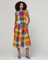 Woman wearing a colorful checkered skirt and top on a plain background
