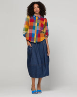 Woman wearing a colorful checkered shirt and denim blue skirt 
