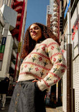 Woman wearing a cream patterned sweater in an urban street setting